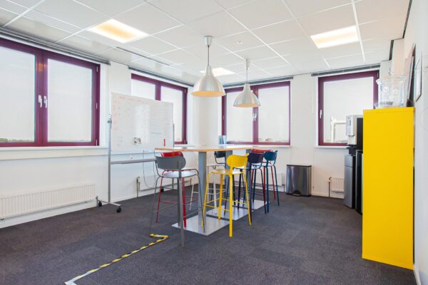 Moderne kantoorruimte aan de Laan der Verenigde Naties met hoge tafel, kleurrijke barkrukken en grote ramen.